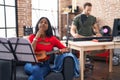 Young indian woman playing ukulele at music studio serious face thinking about question with hand on chin, thoughtful about