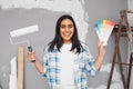 Young Indian woman poses with paint, brush, swatches getting ready to paint wall