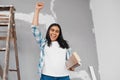 Young Indian woman raises fist proud of DIY construction progress carry timber