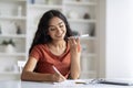 Young indian woman sitting at table, talking on mobile phone Royalty Free Stock Photo