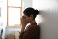 Young Indian woman standing in domestic laundry room and crying