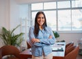 Young Indian woman stands in office arms folded, modern boardroom plants