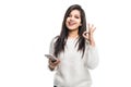 Young beautiful indian woman texting using smartphone over isolated background doing ok sign with fingers, excellent symbol Royalty Free Stock Photo