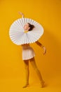 Young indifferent girl in giant jabot collar or neckwear and yellow tights dancing isolated over yellow background