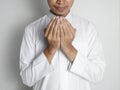 Young Indonesian Muslim man wearing a white robe is raising his hands to pray isolated on white background front view Royalty Free Stock Photo