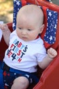 Young infant boy riding in red wagon having fun in the park for July Fourth Royalty Free Stock Photo