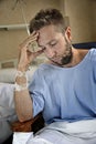 Young injured man in hospital room sitting alone in pain worried for his health condition