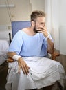 Young injured man in hospital room sitting alone in pain worried for his health condition