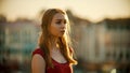 A young inspired woman in red dress standing on the roof - bright sunset