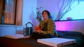 Young interested man sitting on the bed watching TV and eating chips