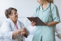 Young intern doctor with pad and stethoscope and elderly grandmother with cane