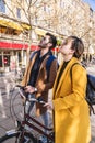 Young international couple looks up, holds bicycle