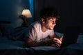 Young internet addict man networking concentrated late at night on bed with laptop in social media addiction or