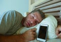 Young internet addict man sleeping on bed holding mobile phone in his hand in smartphone and social media overuse and online addic Royalty Free Stock Photo