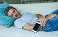 Young internet addict man sleeping on home couch holding mobile phone in his hand in smartphone and social media overuse and onlin