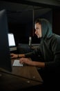 Young internet hacker in hood sitting at monitors Royalty Free Stock Photo