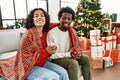 Young interracial couple drinking coffee sitting on the sofa by christmas tree at home Royalty Free Stock Photo