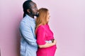Young interracial couple expecting a baby, touching pregnant belly looking to side, relax profile pose with natural face and Royalty Free Stock Photo