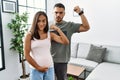 Young interracial couple expecting a baby, touching pregnant belly strong person showing arm muscle, confident and proud of power Royalty Free Stock Photo