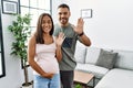 Young interracial couple expecting a baby, touching pregnant belly waiving saying hello happy and smiling, friendly welcome Royalty Free Stock Photo