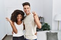 Young interracial couple holding keys of new home celebrating victory with happy smile and winner expression with raised hands Royalty Free Stock Photo