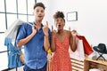 Young interracial couple holding shopping bags at retail shop amazed and surprised looking up and pointing with fingers and raised Royalty Free Stock Photo