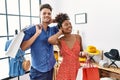 Young interracial couple holding shopping bags at retail shop smiling confident touching hair with hand up gesture, posing Royalty Free Stock Photo