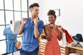 Young interracial couple holding shopping bags at retail shop smiling with happy face looking and pointing to the side with thumb Royalty Free Stock Photo