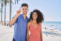 Young interracial couple outdoors on a sunny day showing and pointing up with finger number one while smiling confident and happy Royalty Free Stock Photo