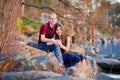 Young interracial couple sitting together on rocky shoreline by