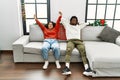 Young interracial couple smiling happy relaxing with hands on head sitting on the sofa at home Royalty Free Stock Photo