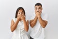 Young interracial couple standing together in love over isolated background shocked covering mouth with hands for mistake Royalty Free Stock Photo