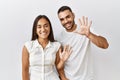 Young interracial couple standing together in love over isolated background showing and pointing up with fingers number ten while Royalty Free Stock Photo