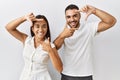 Young interracial couple standing together in love over isolated background smiling making frame with hands and fingers with happy Royalty Free Stock Photo