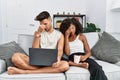 Young interracial couple using laptop at home sitting on the sofa tired rubbing nose and eyes feeling fatigue and headache Royalty Free Stock Photo