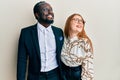 Young interracial couple wearing business and elegant clothes looking away to side with smile on face, natural expression Royalty Free Stock Photo
