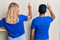 Young interracial couple wearing casual clothes posing backwards pointing ahead with finger hand Royalty Free Stock Photo