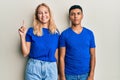 Young interracial couple wearing casual clothes showing and pointing up with finger number one while smiling confident and happy Royalty Free Stock Photo