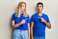 Young interracial couple wearing casual clothes surprised pointing with finger to the side, open mouth amazed expression Royalty Free Stock Photo