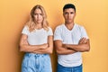 Young interracial couple wearing casual white tshirt skeptic and nervous, disapproving expression on face with crossed arms