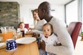 Young interracial family with little children having breakfast. Royalty Free Stock Photo