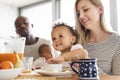 Young interracial family with little children having breakfast. Royalty Free Stock Photo