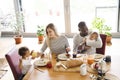 Young interracial family with little children having breakfast. Royalty Free Stock Photo