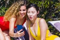 Young interracial girls with phone on a sun lounger