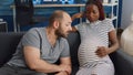 Young interracial parents sitting together on couch Royalty Free Stock Photo