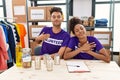 Young interracial people wearing volunteer t shirt at donations stand smiling with hands on chest with closed eyes and grateful