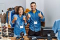 Young interracial people working at retail boutique success sign doing positive gesture with hand, thumbs up smiling and happy Royalty Free Stock Photo