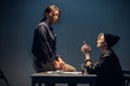 A young investigator an asian woman sits on a table during the interrogation of a pretty criminal