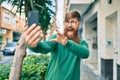 Young irish man with redhead beard smiling happy and doing video call using smartphone at the city