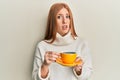 Young irish woman drinking a cup of coffee clueless and confused expression